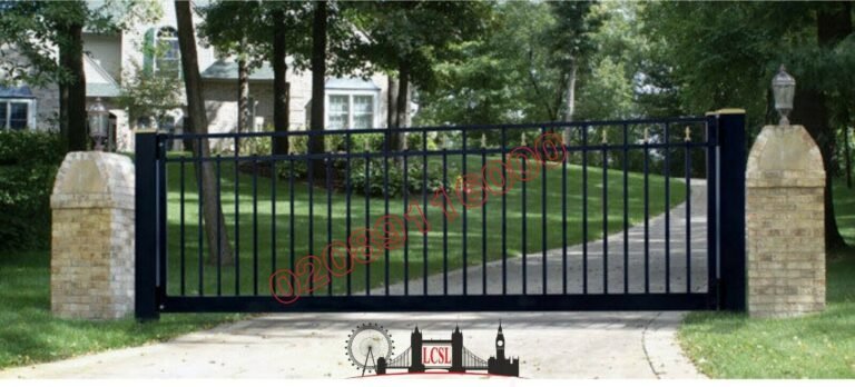 Black wrought iron driveway gate sliding between brick pillars on sloped drive