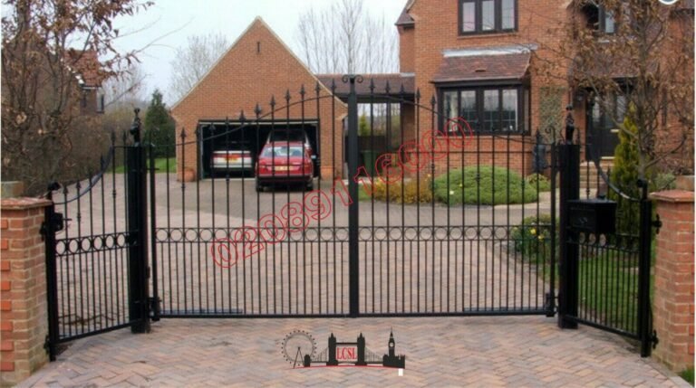 Black wrought iron driveway gates with arched top and spear finials between brick pillars