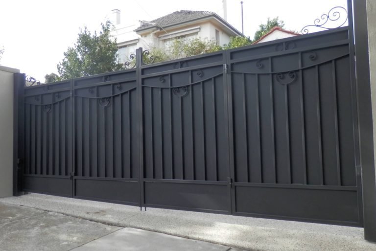 Dark charcoal metal bifold driveway gates with scroll detail and vertical privacy slats