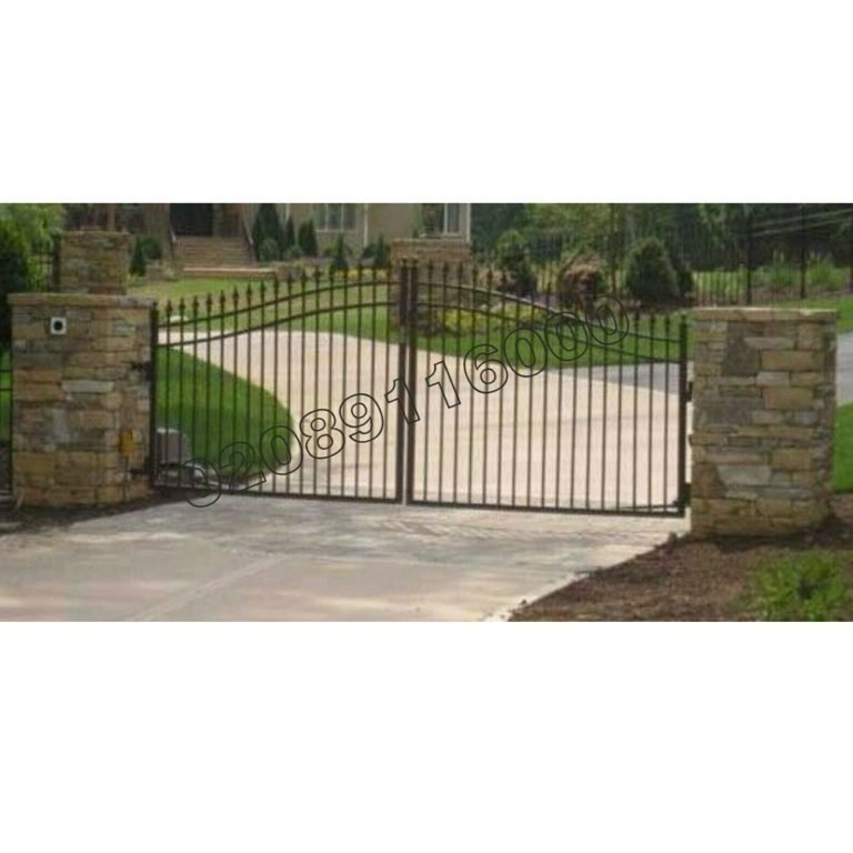 Black metal double swing driveway gate with bell-curved top between stone pillars