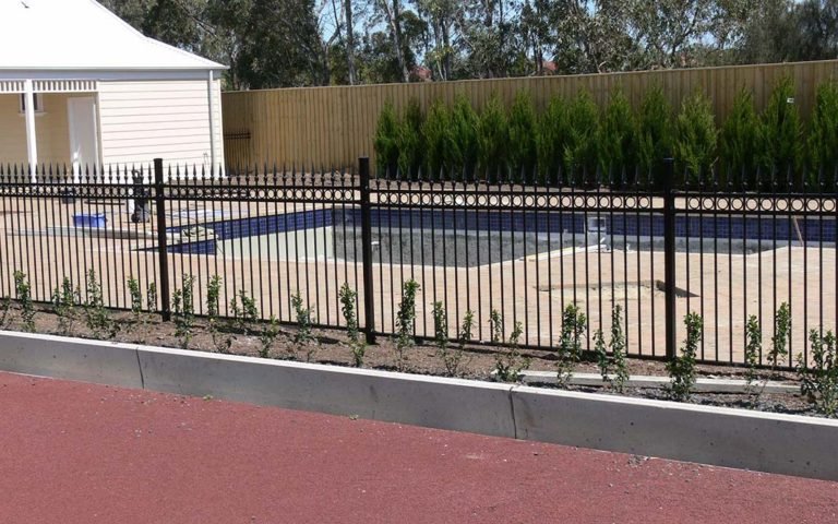 Black spear top metal railings with ring detail fitted along a poolside boundary