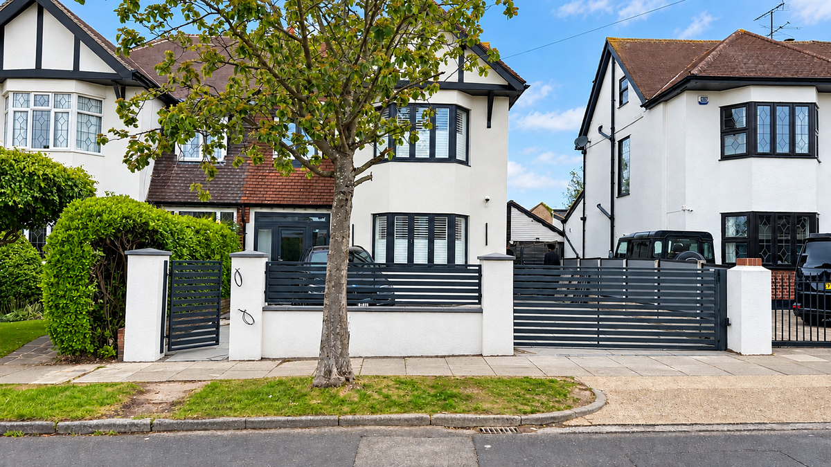 Dark grey horizontal slat driveway gate with matching fencing and pedestrian gate between white pillars.