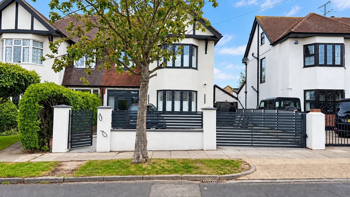 Home 15 Dark grey horizontal slat driveway gate with matching fencing and pedestrian gate between white pillars.