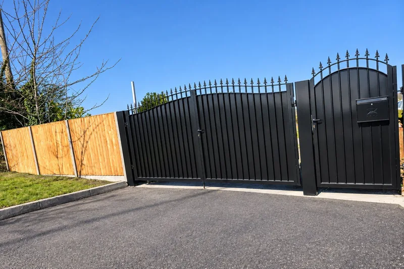 Black steel driveway gates with matching pedestrian gate on a tarmac drive