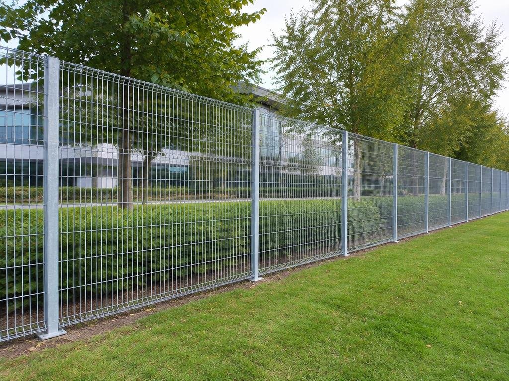 Continuous galvanised welded-mesh fence beside a landscaped UK business park